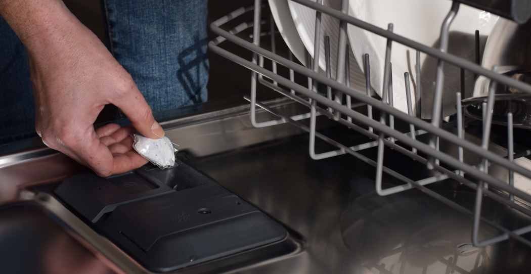 photo of dishwashing detergent pod being put into the soap dispenser of a dishwasher